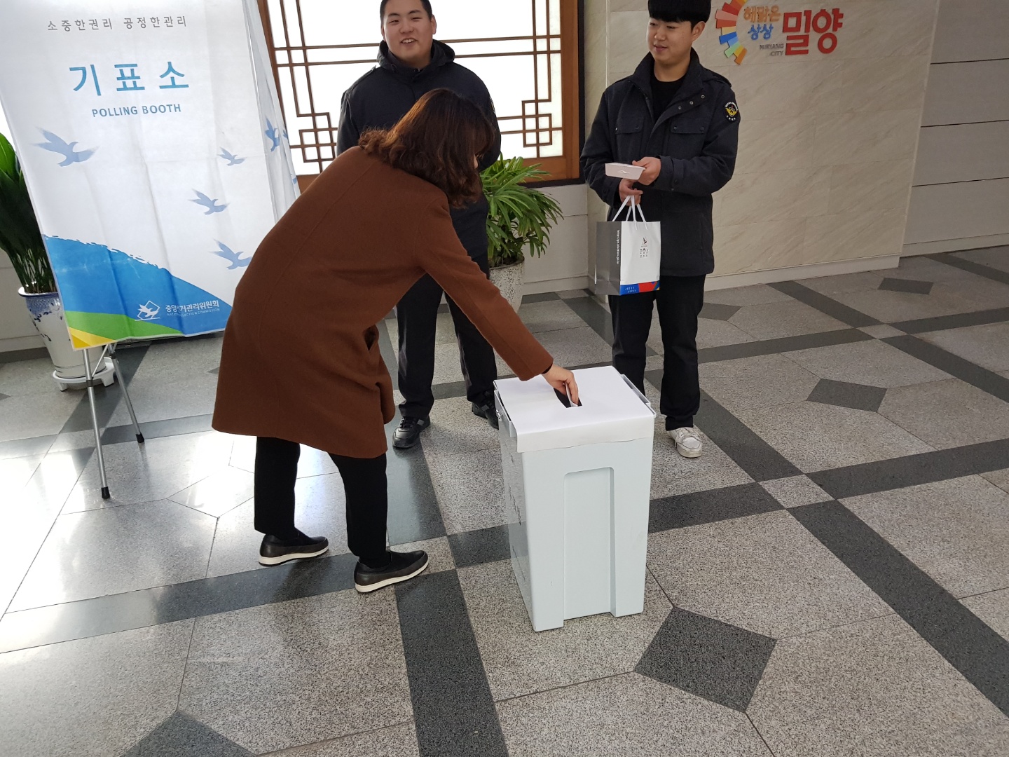 밀양시민대학 참가자가 사전투표체험을 하고 투표용지를 투표함에 넣고있는 모습입니다.
