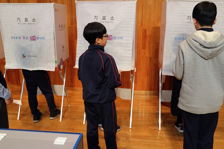 기표소 앞에서 순서를 기다리는 학생과 투표하는 학생들의 모습