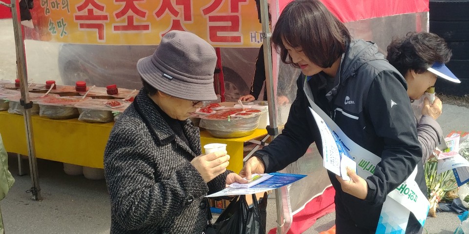 시장 방문객에게 조합장선거에 대해 안내하는 사진