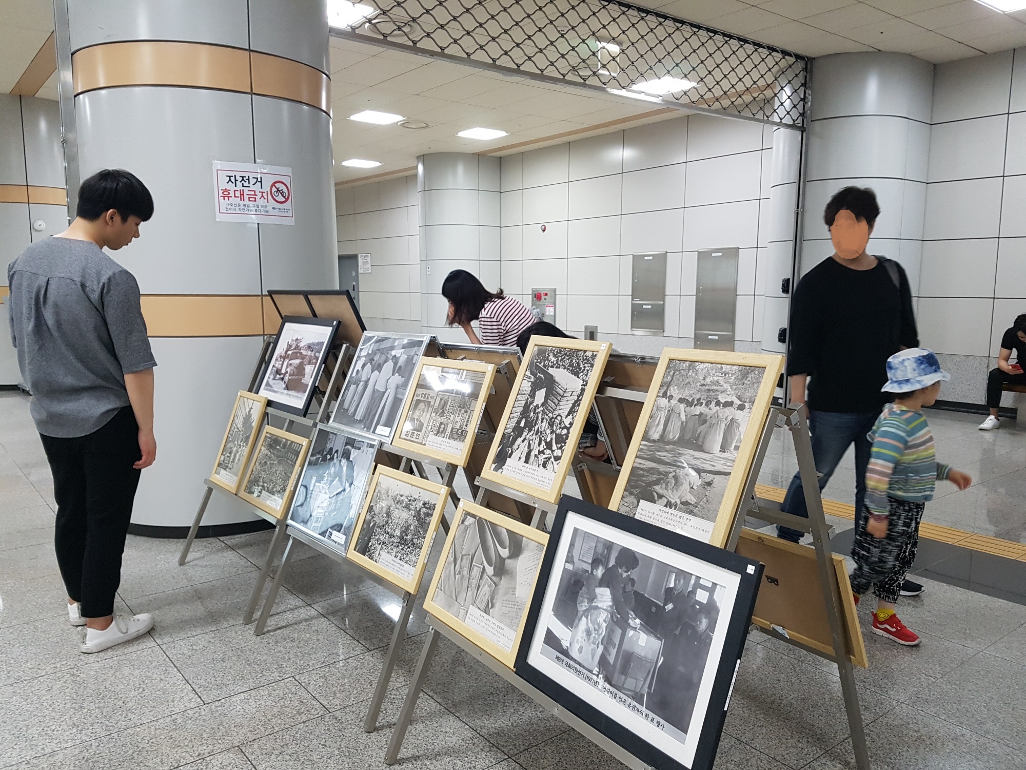 지하철역을 지나가던 시민들이 전시되어 있는 선거사진들을 관람하고 있는 모습