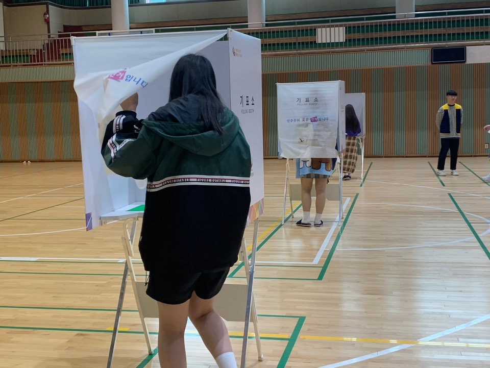 학생들이 기표소에서 투표하는 장면