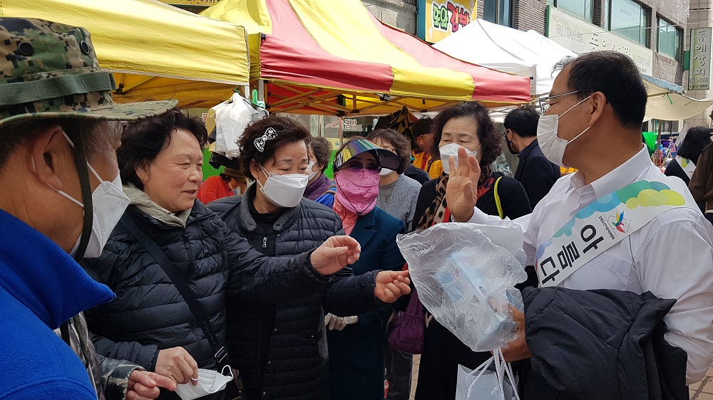 (사진6) 양양군위원회 공정선거지원단이 마스크를 착용하지 않은 시장 방문객들에게 일회용 마스크를 배부하며 투표참여 안내를 하고 있다