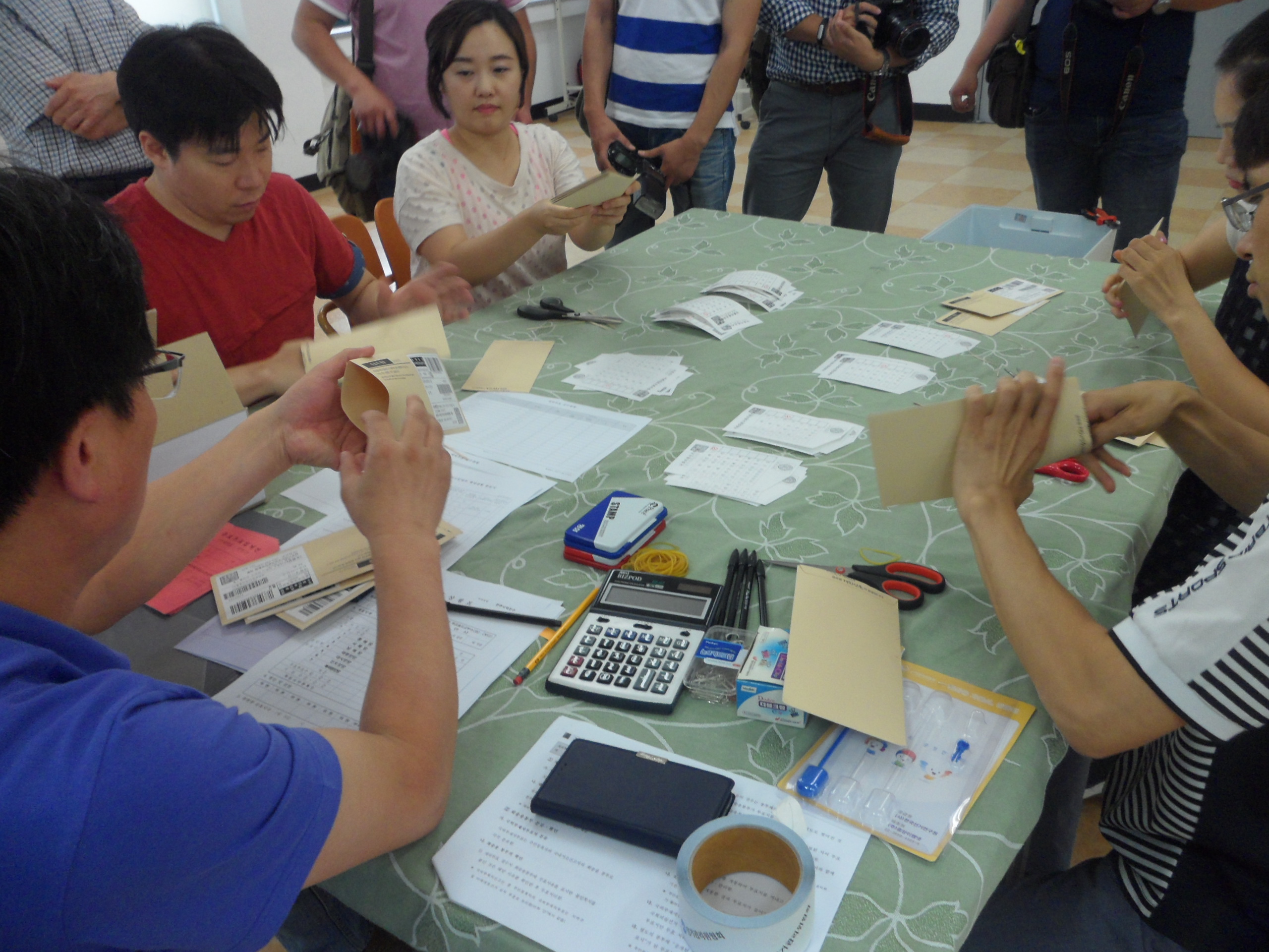 선거관리위원회 직원들이 모의 재외선거 회송용 봉투에 들어있는 투표지를 꺼내어 분류하고 있는 모습