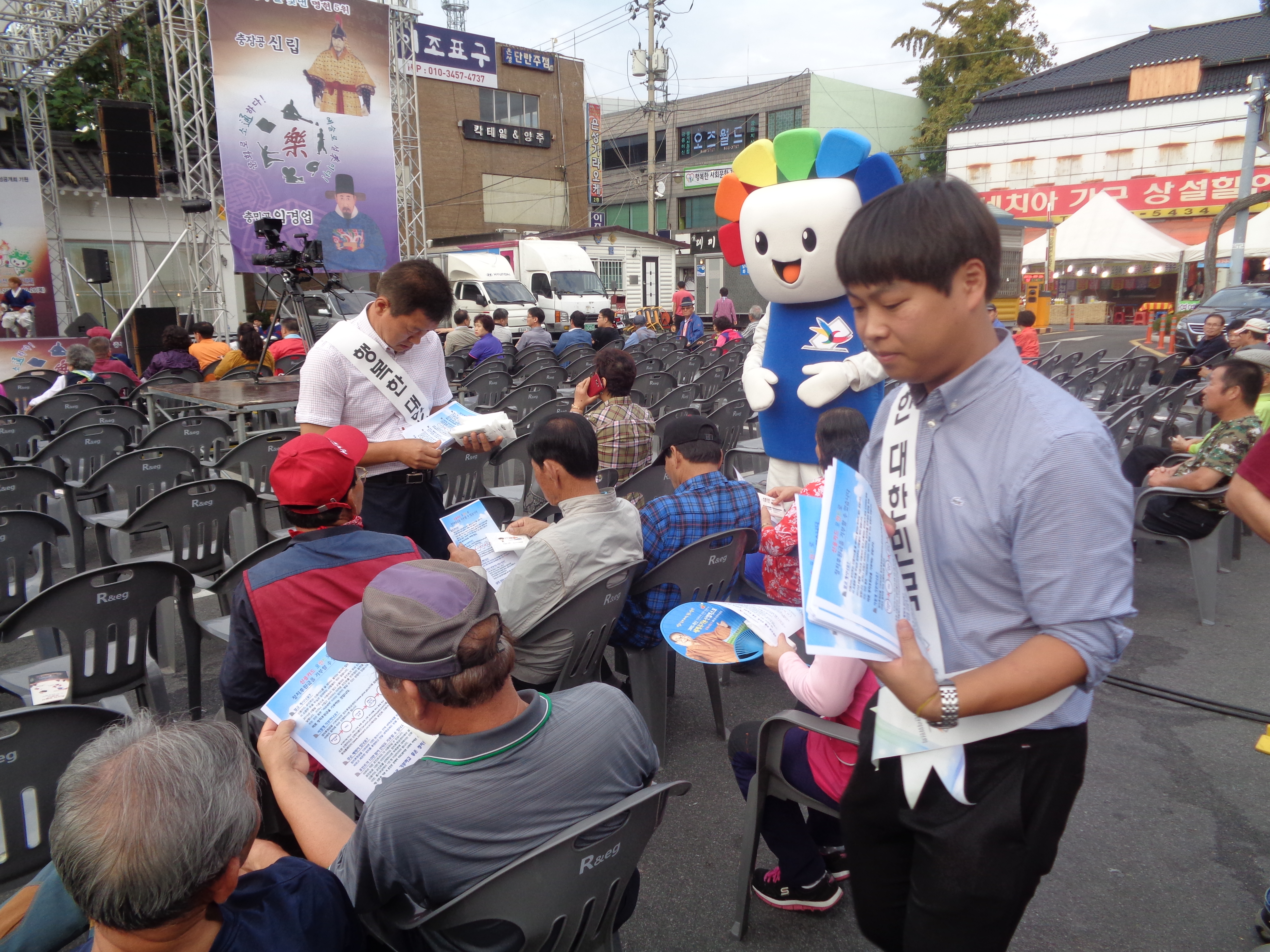 직원들이 행사 참석자에게 정치후원금 안내 홍보 리플렛 나눠 주는 모습