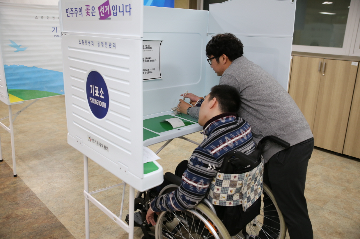기표소에서 활동보조인의 도움을 받아 투표하는 모습