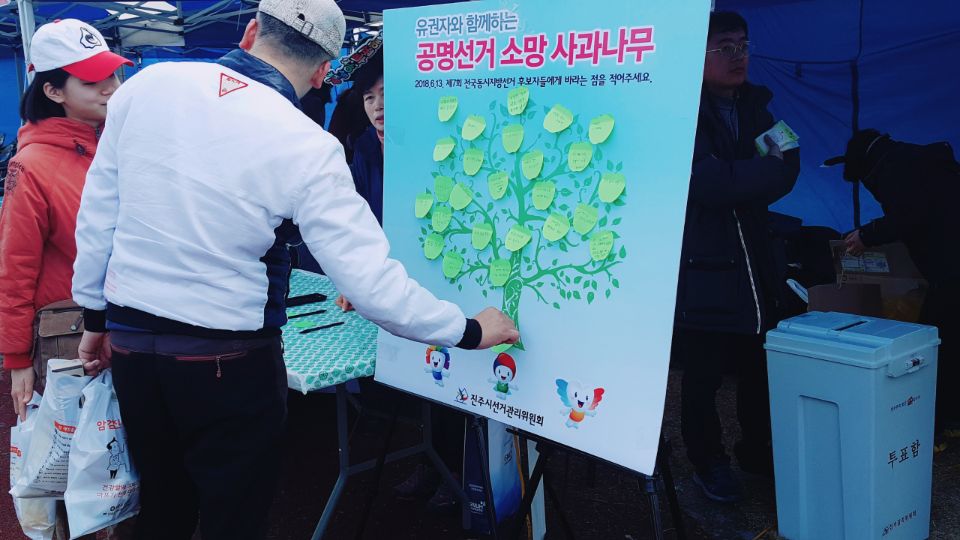 유권자와 함께하는 소망사과나무에 소망 포스트잇을 부착하는 모습
