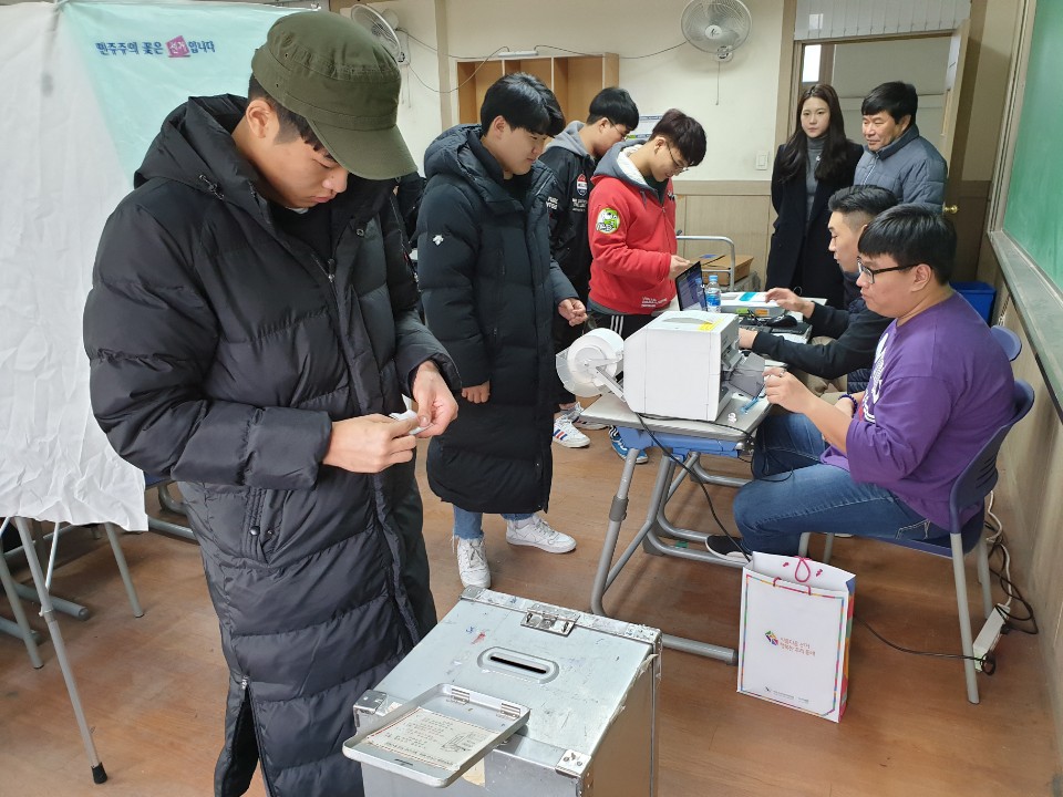 경성고 학생이 기표한 투표지를 투표함에 투입하기 위하여 투표지를 접고 있는 모습 사진입니다.